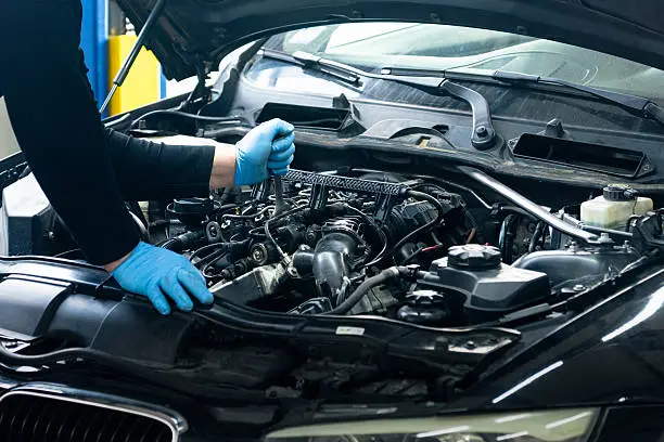 Mechanic working on car engine at Maxim Motors