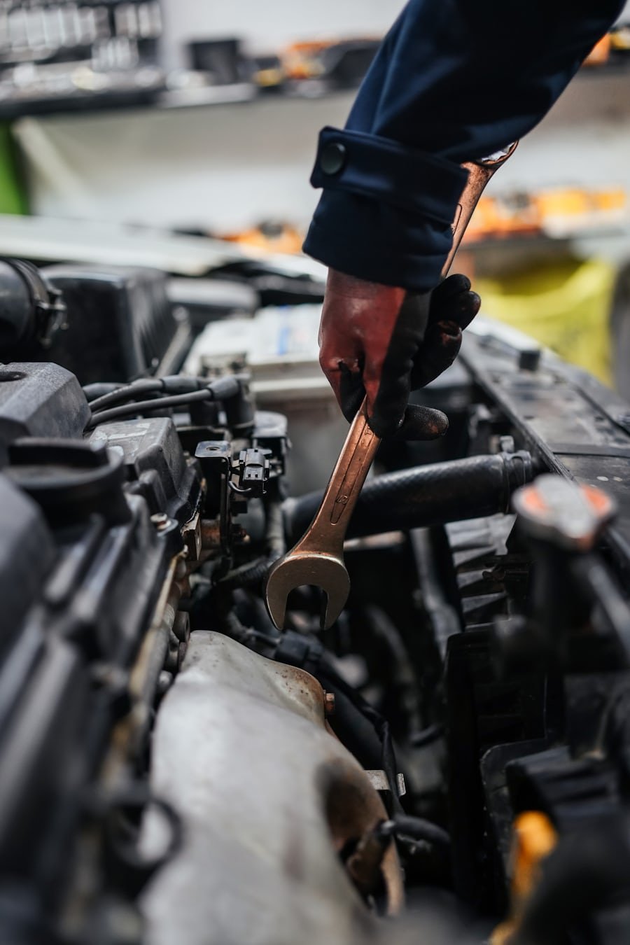Mechanic using wrench deep inside engine bay at Maxim Motors